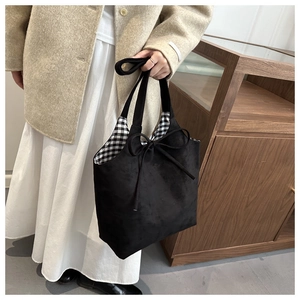 Detail of black suede tote bag featuring a bow tie and stylish plaid fabric lining