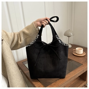 Detail of black suede tote bag featuring a bow tie and black and white checkered lining