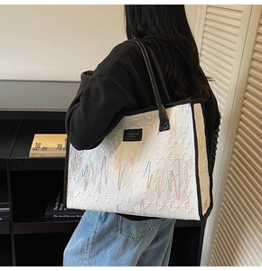 Détail du sac cabas blanc avec gaufrage texturé et broderies de vagues colorées