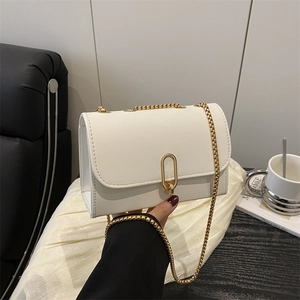 Minimalist white leather crossbody bag with gold chain strap and oval metal lock closure