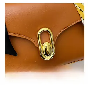 Detail of vintage square bag with golden oval lock and colorful silk scarf handle
