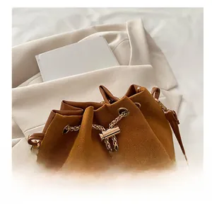 Macro shot of brown suede bucket bag with gold chain drawstring and fine texture