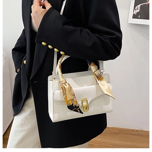 Detail of white leather box bag with vintage floral scarf wrapped handle and gold lock