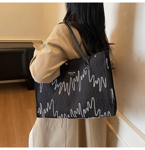 Détail du grand sac cabas noir matelassé avec surpiqûres blanches et étiquette logo
