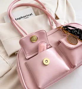 Macro detail of a pink leather handbag with magnetic gold buckles and tennis racket pendant