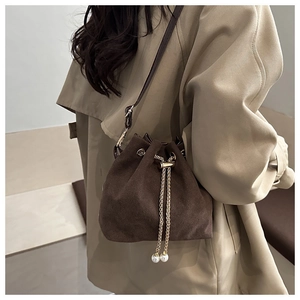 Close-up of brown frosted bucket bag with gold chain drawstring and pearl detail
