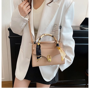 Detail of beige leather crossbody bag with silk scarf handle and gold twist lock