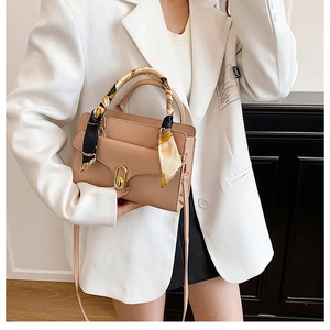 Beige structured handbag with scarf handle decoration shown in a professional lifestyle shot