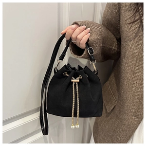 Detail of black bucket bag featuring golden chain drawstring and elegant pearl charms