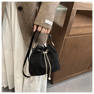 Detail of matte bucket bag featuring gold chain drawstring and elegant pearl charms