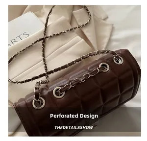 Detail of quilted dark brown bag with metal eyelets and silver chain shoulder strap