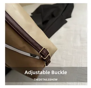 Detail showing the adjustable golden buckle and stitching on brown leather shoulder strap