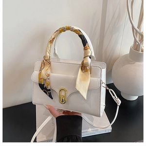 Detail of white PU leather handbag with silk scarf handle and golden oval lock buckle