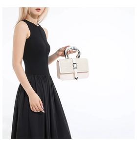 Detail of cream woven leather handbag with a silver geometric handle and heart buckle