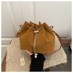 Detailed macro view of brown suede bucket bag with gold chain and pearl charms