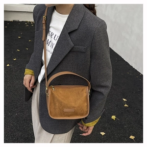 Close-up of brown suede tote bag featuring adjustable straps and gold-tone hardware