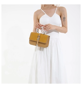 Detail of contrast color handbag with yellow herringbone flap and wave metal handle
