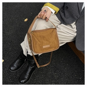 Detail of tan faux suede tote bag with adjustable shoulder strap and gold hardware