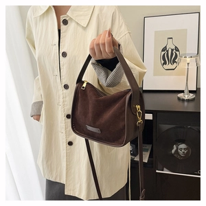 Detail of dark brown faux suede tote bag with golden metal hardware and strap hooks