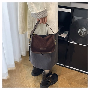 Detail of a brown matte suede tote bag with gold zipper and minimalist leather brand tag