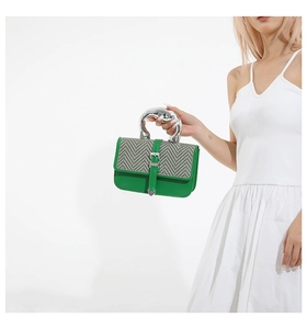 Detail of green leather handbag with silver metallic handle and textured woven flap