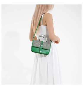 Detail of artistic silver metal handle and green leather bag with herringbone pattern