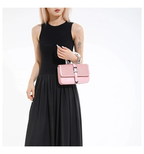 Close-up of pink crossbody bag with woven flap, metal ring handle and heart-shaped buckle