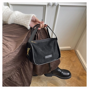 Detail of black frosted suede tote bag with elegant golden hardware and smooth leather handle