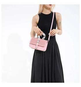 Detailed view of pink woven crossbody bag with silver arched handle and heart buckle