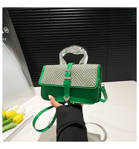 Detail of green leather handbag featuring woven flap, metal handle and thin shoulder strap