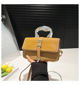 Close-up of woven yellow texture and brown leather base of this stylish handbag