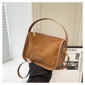 Detail of brown suede tote bag with smooth leather straps and golden metal zipper