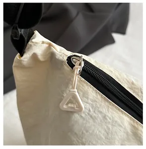 Detail of smooth black zipper and white plastic puller on off-white fabric shoulder bag