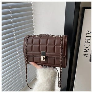 Detail of dark brown quilted crossbody bag with silver chain strap and metal lock closure