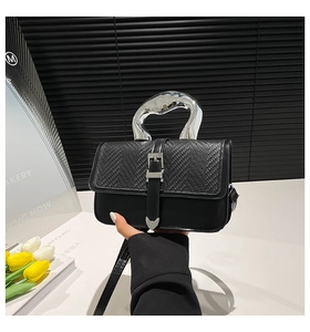 Detail of minimalist black leather crossbody bag with artistic silver metal handle