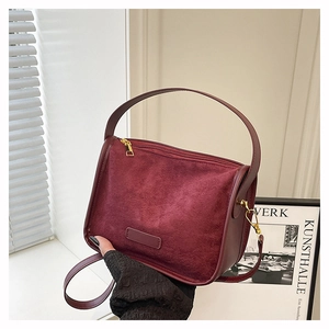 Detail view of the burgundy suede tote bag showing texture contrast and golden hardware