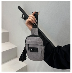 Détail du sac de poitrine en nylon gris avec logo en caoutchouc et bandoulière réglable