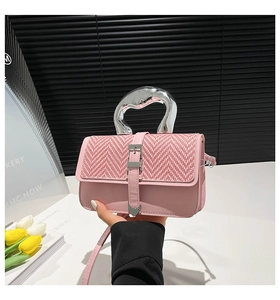 Detail of pink leather woven bag featuring silver irregular metal handle and heart charm