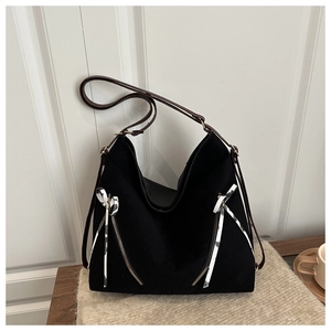 Detail of black canvas tote bag with brown leather straps and striped ribbon accent