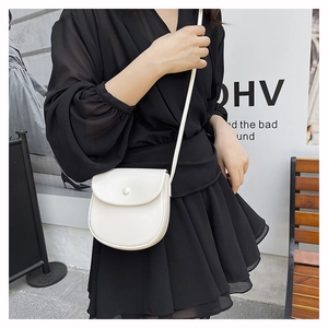 Detail of a white minimalist saddle bag showing a round button and high-quality faux leather