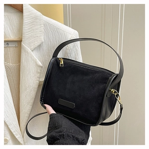 Detail of black matte suede tote bag with gold hardware and smooth leather strap