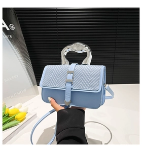 Detail of light blue woven leather crossbody bag with unique silver metallic handle