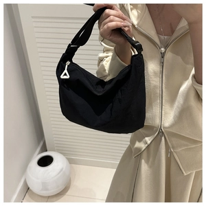 Detail view of black nylon dumpling bag with triangular zipper and adjustable strap