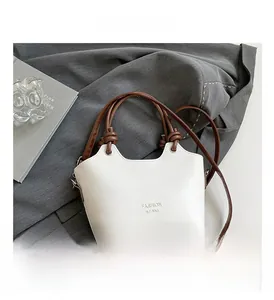 Detail of the knot handle and metal buckle on the cream bucket bag with brown straps