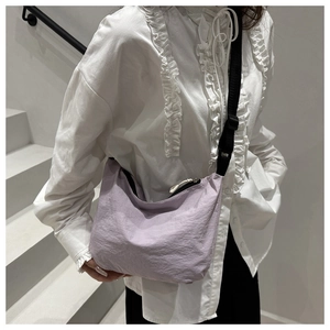 Close-up of lavender nylon crossbody bag with adjustable strap on white background