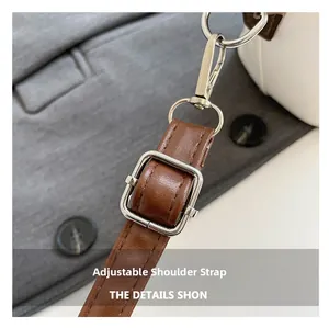 Detail view of the brown adjustable shoulder strap with silver buckle on the bucket bag