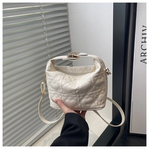Gedetailleerd beeld van witte bucketbag met hartstiksel, metalen gesp en leren riem