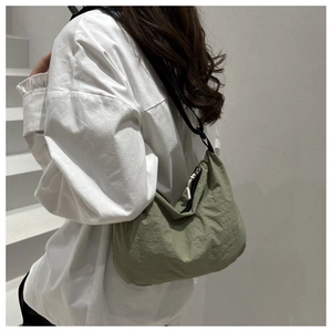 Side view of avocado green crescent bag with adjustable black strap on person