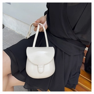 Chic cream-colored horseshoe saddle bag shown in use with adjustable leather strap