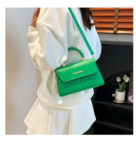 Détail du petit sac vert avec poignée tressée et bordure métallique dorée élégante